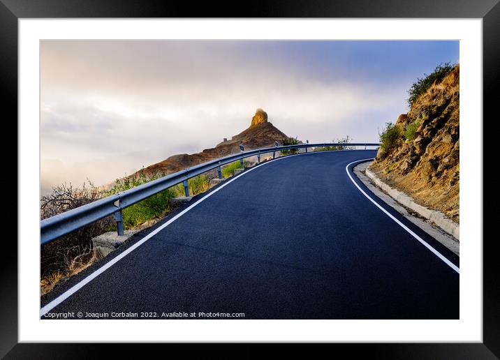 A mountain road approaches the famous Roque Bentayga through the Framed Mounted Print by Joaquin Corbalan