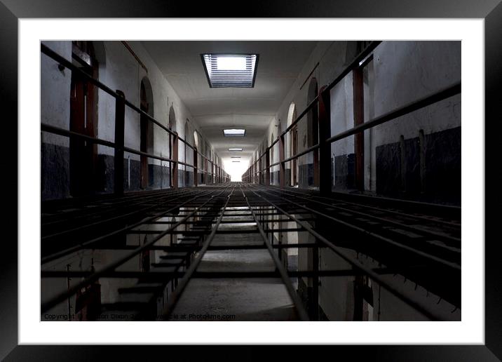 Light at the end of a corridor of cells in an abandoned prison in Kuala Lumpur Framed Mounted Print by Gordon Dixon