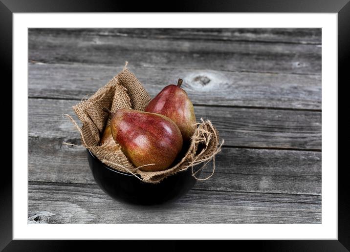 Raw whole pears inside of bowl on aged wooden table in close up  Framed Mounted Print by Thomas Baker