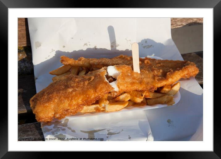 Golden brown battered fish with chips and a wooden fork in paper - delicious Framed Mounted Print by Gordon Dixon