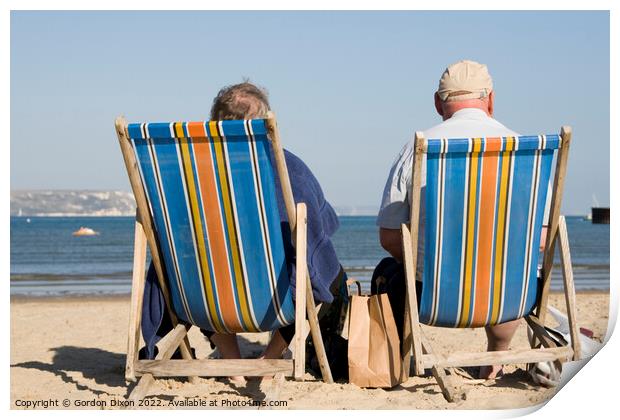 Elderly couple in bright striped deckchairs on the sand at Weymouth Print by Gordon Dixon