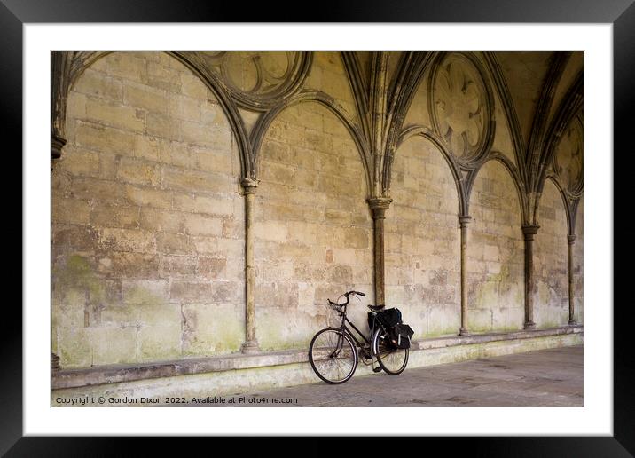 A priest's bicycle leaning up against a wall in the Cloister's Courtyard of Salisbury Cathedral, Wiltshire Framed Mounted Print by Gordon Dixon
