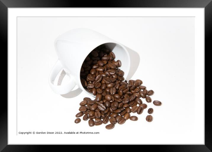Roasted coffee beans spilling out of a mug - white background Framed Mounted Print by Gordon Dixon