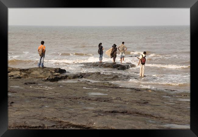 Group of Indian students stand on rocks at Mumbai as the tide comes in Framed Print by Gordon Dixon