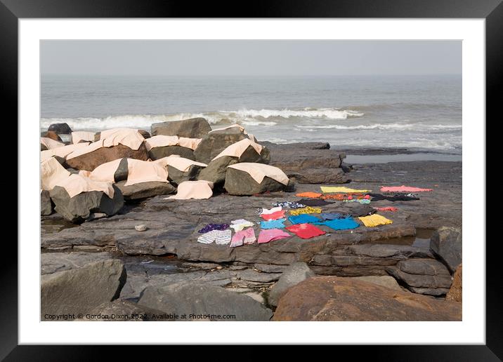 Freshly laundered clothes and fabrics drying on rocks by the sea at Mumbai, India Framed Mounted Print by Gordon Dixon