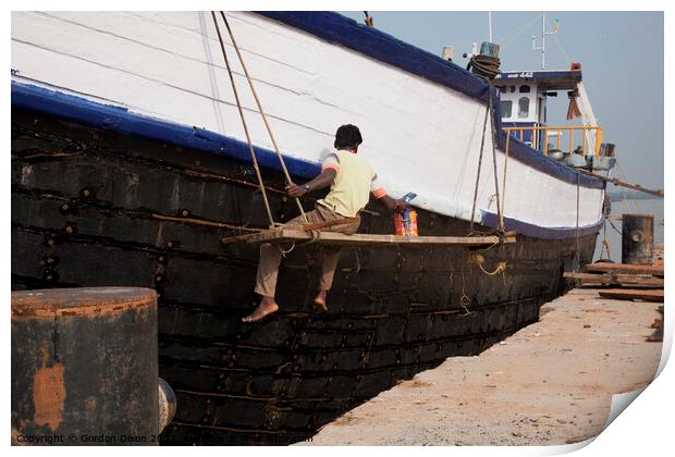 A ship repairer paints an old wooden ship in Mangalore, India Print by Gordon Dixon