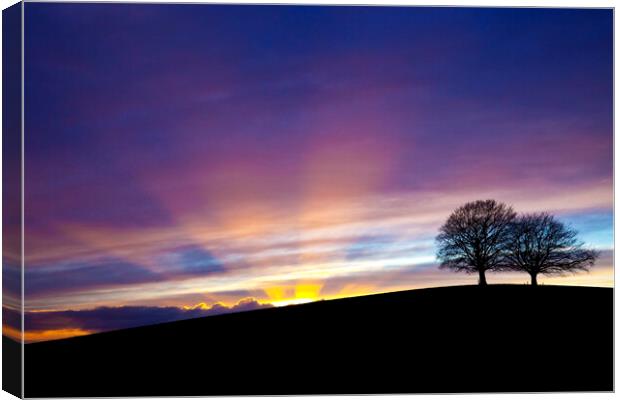 Dramatic sunset behind Spir Hill with sunbeams Canvas Print by Gordon Dixon