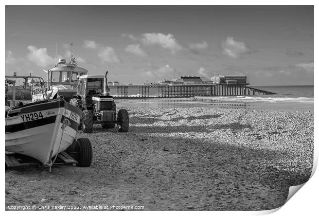 Black and white vintage photo of fishing boats and equipment on Cromer beach on the North Norfolk Coast. In the distance is the Victorian era pier Print by Chris Yaxley