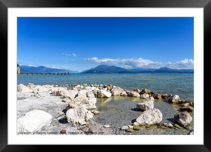 Calm water lake in Garda, Italy with a wooden walkway on a sunny Framed Mounted Print by Joaquin Corbalan