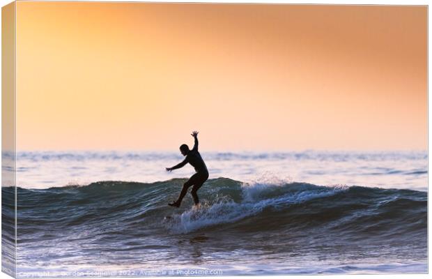 An acrobatic surfer riding a wave in Fistral Bay i Canvas Print by Gordon Scammell
