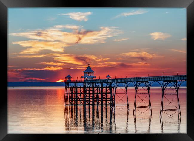 Clevedon Pier at sunset with colourful reflection on the sea Framed Print by Rory Hailes