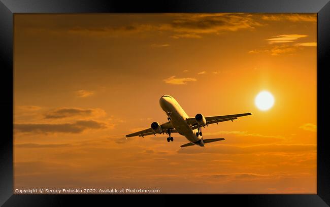 Passenger commercial aircraft flying under the clouds in sunset light. Framed Print by Sergey Fedoskin