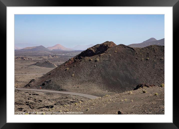 Lone figure walking in the Timanfaya National Park Framed Mounted Print by Keith Bowser