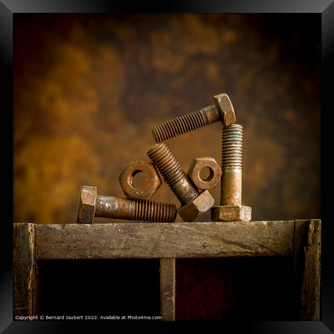 Rusty bolt on a wooden surafce Framed Print by Bernard Jaubert