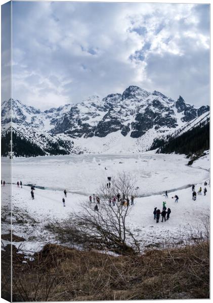 Zakopane, Poland - May 04, 2022: Panorama of Morskie oko frozen lake covered with snowy tatra mountains with people or tourists walking on snow Canvas Print by Arpan Bhatia