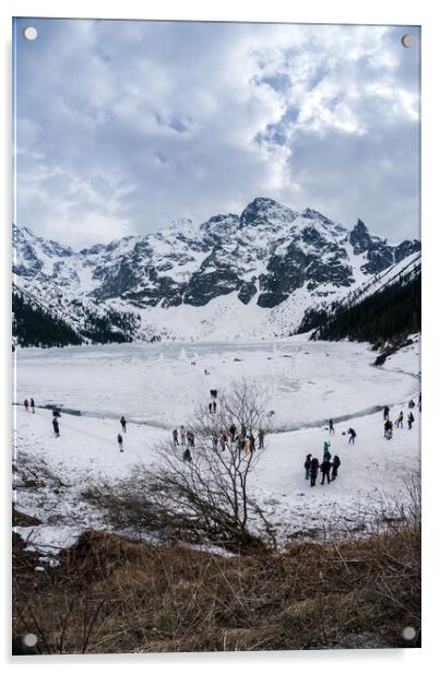 Zakopane, Poland - May 04, 2022: Panorama of Morskie oko frozen lake covered with snowy tatra mountains with people or tourists walking on snow Acrylic by Arpan Bhatia