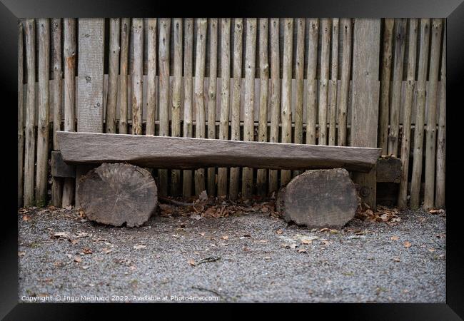 Bench made with logs of wood by a wooden fence Framed Print by Ingo Menhard