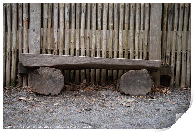 Bench made with logs of wood by a wooden fence Print by Ingo Menhard