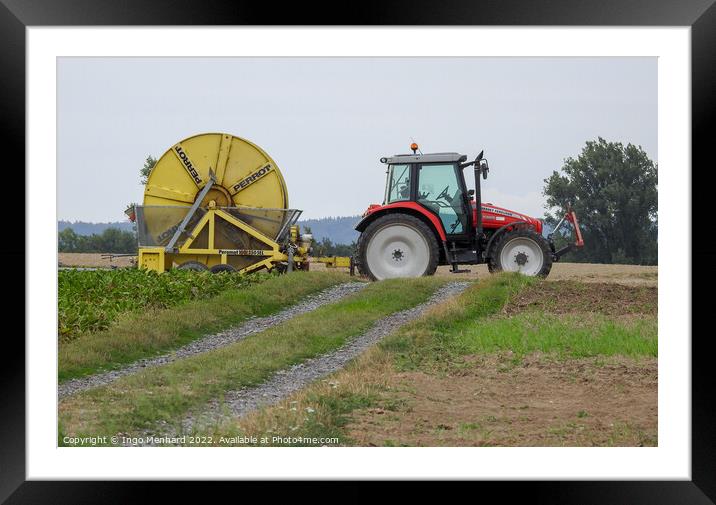 A red farm tractor with a yellow trailer at work on a field Framed Mounted Print by Ingo Menhard