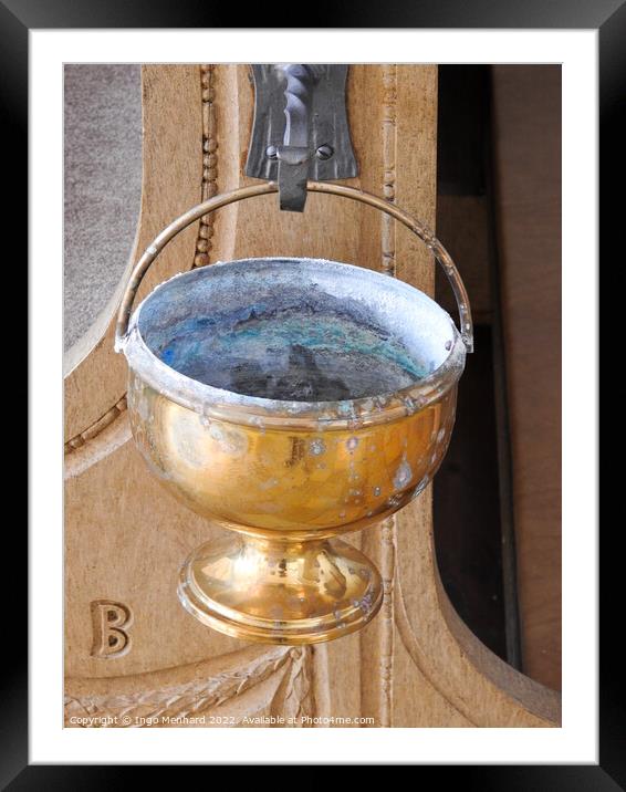 A vertical shot of an old golden goblet hung from a metal hook in the church Framed Mounted Print by Ingo Menhard