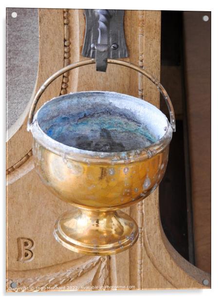 A vertical shot of an old golden goblet hung from a metal hook in the church Acrylic by Ingo Menhard