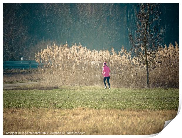 Woman in a pink jacket jogging in the park with dried reed grass background Print by Ingo Menhard