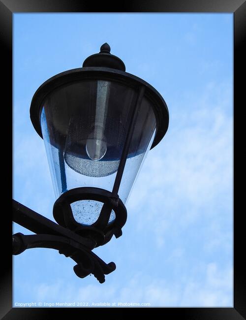 A vertical closeup shot of a street lamp against a cloudy sky Framed Print by Ingo Menhard