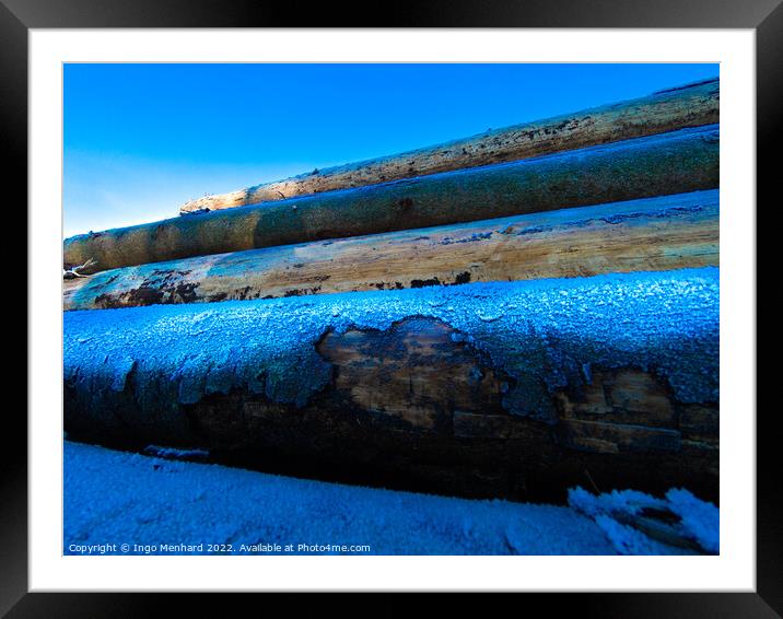 Pile of logs covered with snow at sunset Framed Mounted Print by Ingo Menhard