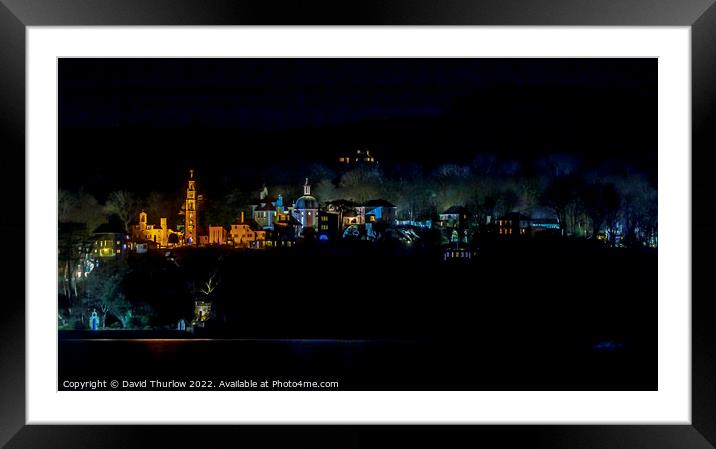 The lights of the Italianate village of Portmeirion illuminate the surrounding trees Framed Mounted Print by David Thurlow