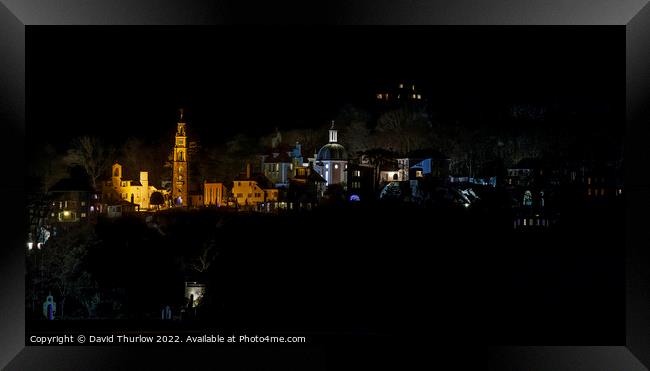 The lights of the Italianate village of Portmeirion illuminate the surrounding trees Framed Print by David Thurlow