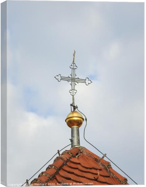 A vertical shot of a metallic cross on a cloudy sky background. Canvas Print by Ingo Menhard