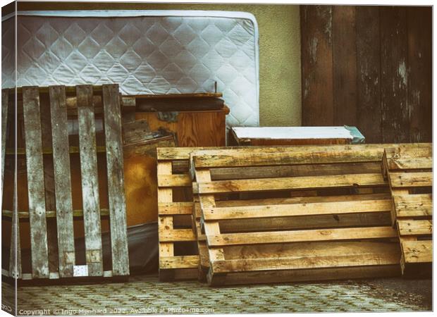 Shot of pallets leaning against the wall with old furniture and mattress Canvas Print by Ingo Menhard