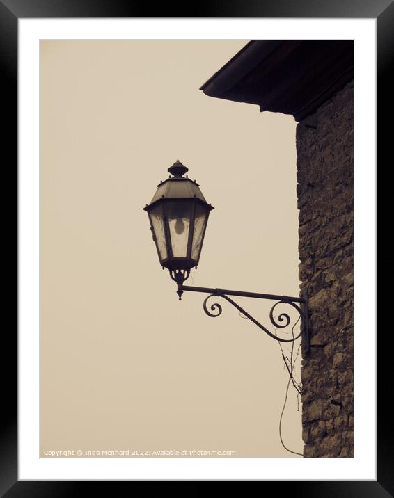 Closeup of a vintage wall-mounted lantern in the light background Framed Mounted Print by Ingo Menhard