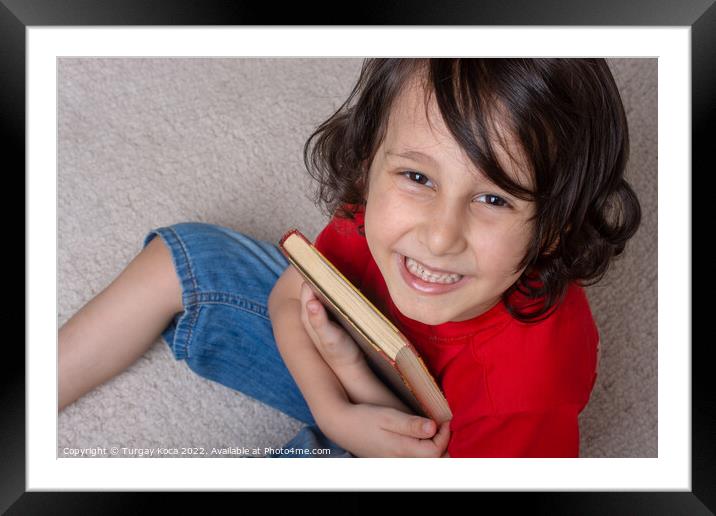 Boy holding book as World book day concept Framed Mounted Print by Turgay Koca