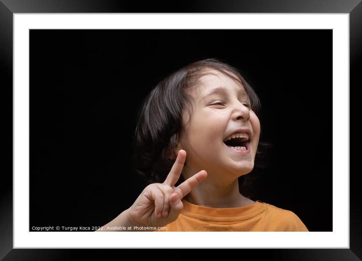 Cheerful little boy with Victory Hand Sign as Vict Framed Mounted Print by Turgay Koca