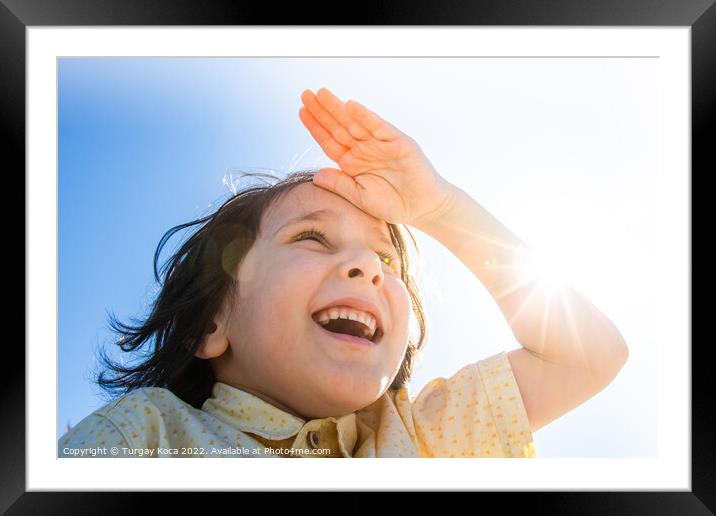 Happy smiling boy in flare sunshine with  hand at  Framed Mounted Print by Turgay Koca