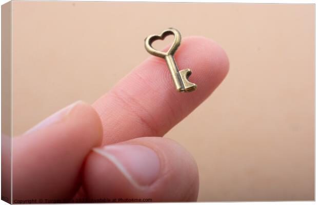 Tiny key with heart shape on the finger tip Canvas Print by Turgay Koca