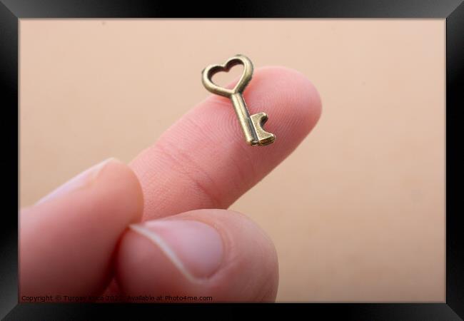 Tiny key with heart shape on the finger tip Framed Print by Turgay Koca