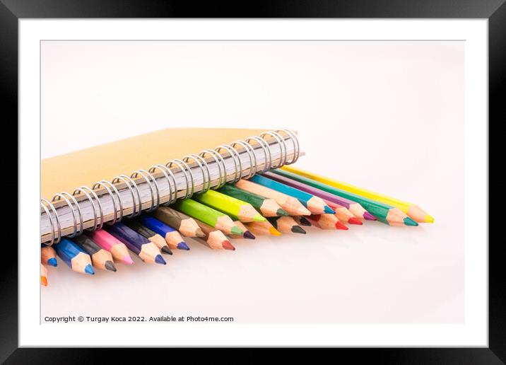 color pencils of various colors near a notebook Framed Mounted Print by Turgay Koca