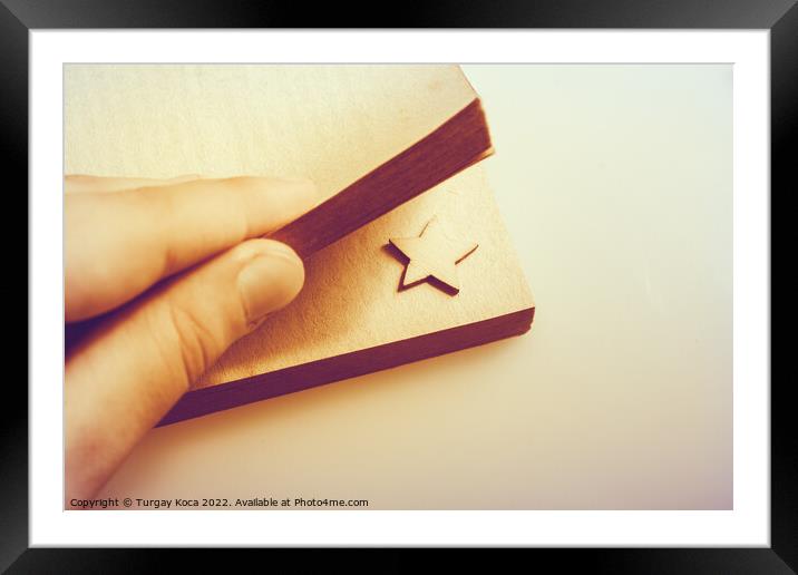 Hand holding a book with a star in pages Framed Mounted Print by Turgay Koca
