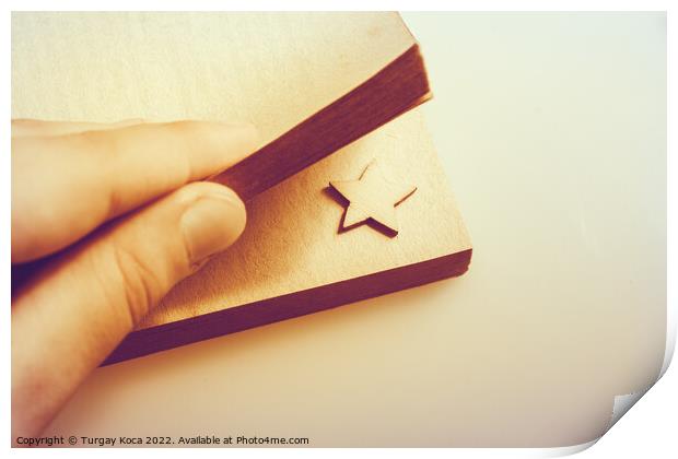 Hand holding a book with a star in pages Print by Turgay Koca