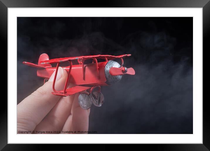 Hand holding a toy plane on black background Framed Mounted Print by Turgay Koca
