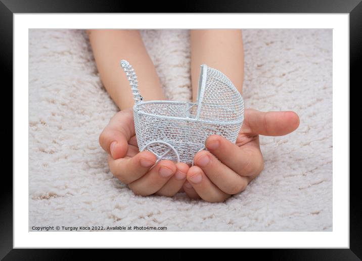 Toy baby carriage in hand made of metal on white background Framed Mounted Print by Turgay Koca
