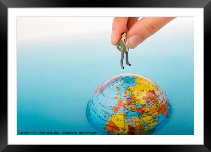 Figurine on the top of the globe in water Framed Mounted Print by Turgay Koca