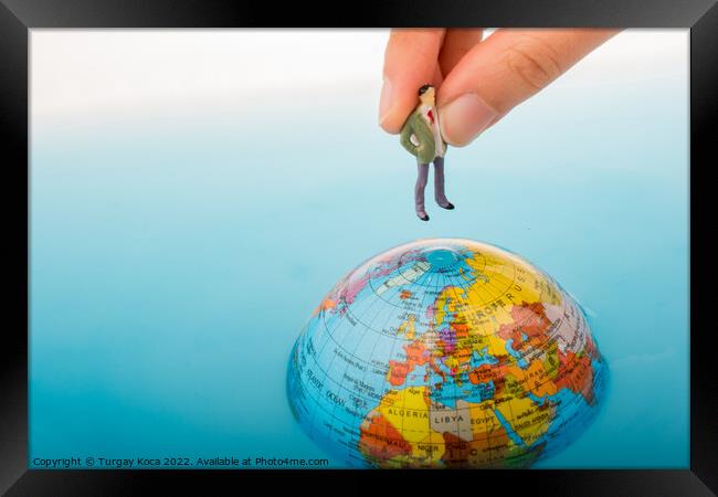 Figurine on the top of the globe in water Framed Print by Turgay Koca