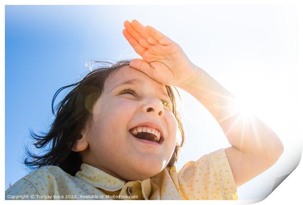 Happy smiling boy in flare sunshine with  hand at forehead Print by Turgay Koca