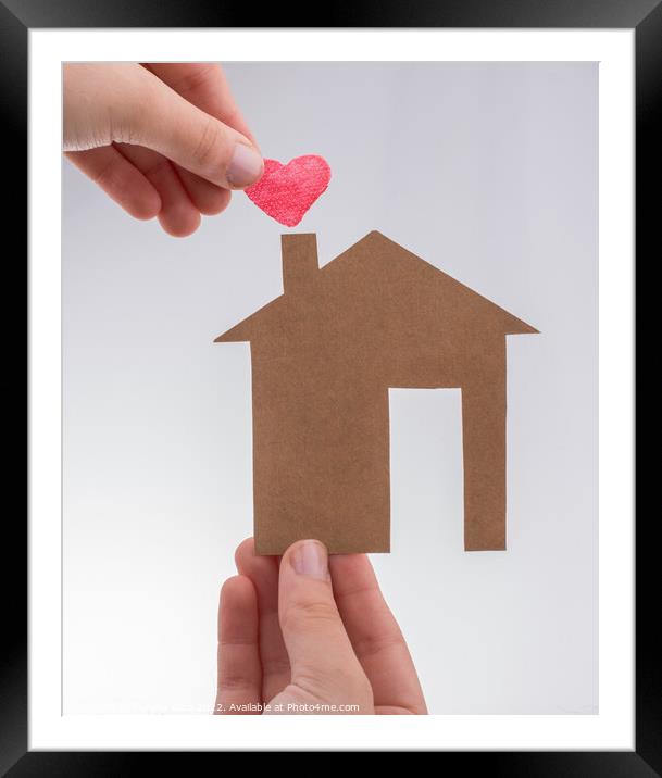 Hand holding a heart on a paper house  Framed Mounted Print by Turgay Koca