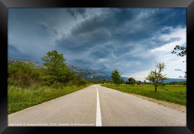 Empty countryside road in valley. Landscape with dramatic sky. A storm is coming from the mountains. Framed Print by Sergey Fedoskin