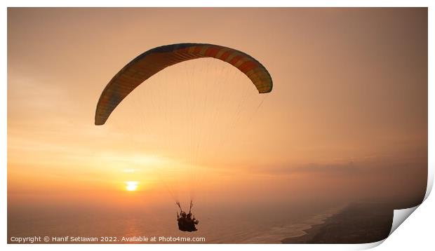 Tandem paragliding over sea and beach while golden Print by Hanif Setiawan