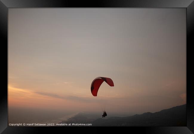 Tandem paragliding over sea and beach at sunset Framed Print by Hanif Setiawan